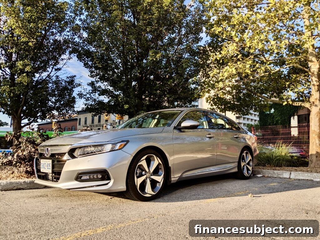 A silver Honda Accord in a parking lot surrounded by trees