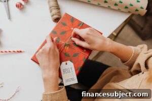 Hands tie a bow on a box wrapped in Christmas paper