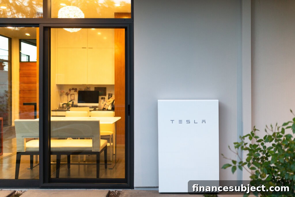 A white rectangular Tesla powerwall on the exterior wall of a house