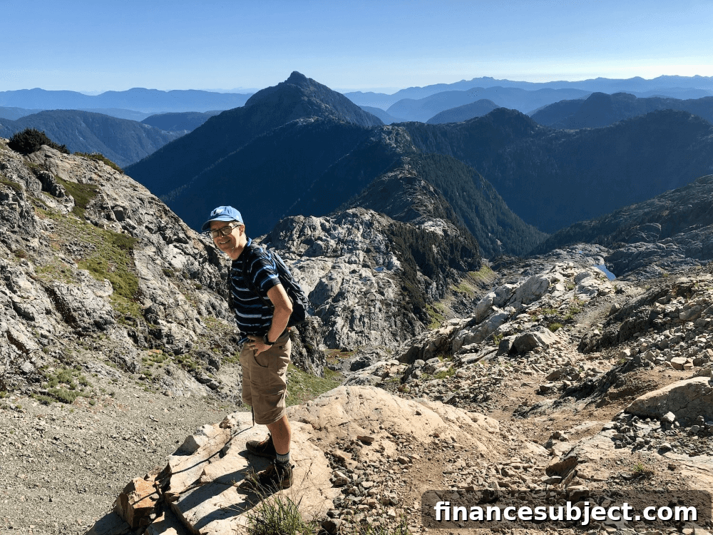 Michael McCullough stands on a hiking trail in front of mountains.