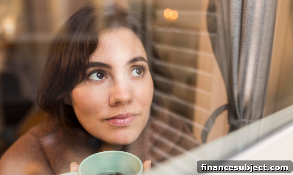 A woman looks hopefully out the window while drinking tea