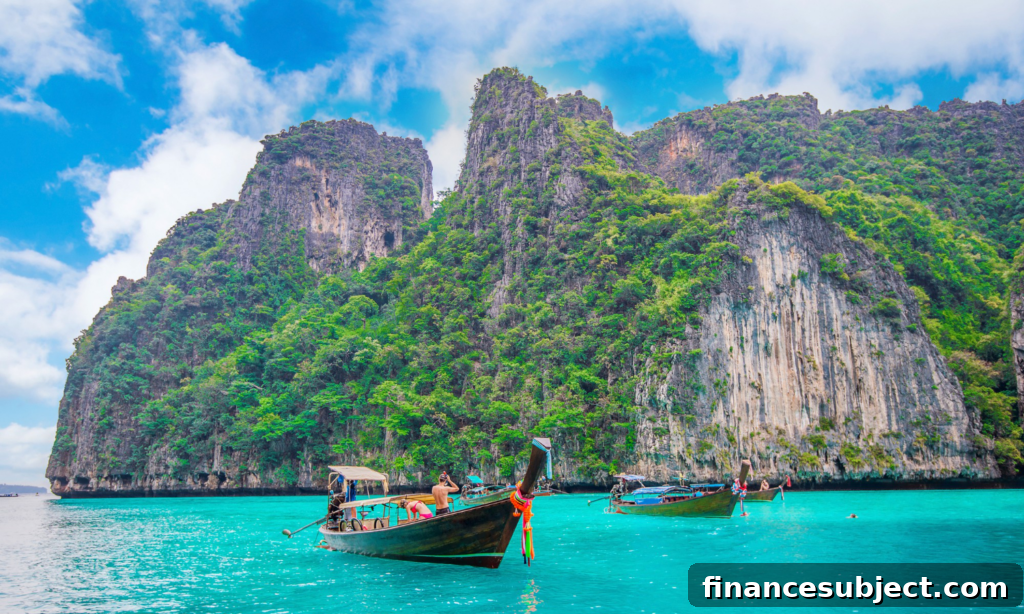 Three boats besides a cliff face in Maya Bay in Thailand